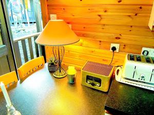 a table with a lamp and a toaster and a radio at Braemar Lodge Cabins in Braemar +14 photos
