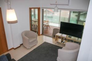 uma sala de estar com cadeiras, uma televisão e uma mesa em Casas e Quintas de Praia em Praia da Barra