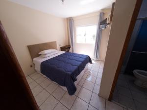 a bedroom with a bed and a bathroom with a window at Nacional Park Hotel Lages in Lages