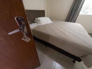 a bedroom with a bed and a door with a tag on it at Nacional Park Hotel Lages in Lages