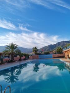 uma grande piscina com montanhas ao fundo em L'oliveraie D'amizmiz em Amizmiz