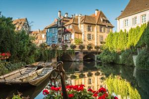 un pont sur une rivière avec des bâtiments et des fleurs dans l'établissement Le Neubau, à Colmar
