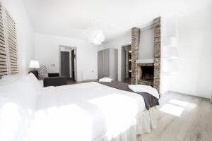een witte slaapkamer met een groot bed en een open haard bij Avet in El Tarter