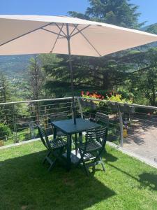 a table and chairs under an umbrella in the grass at Oasi verde in Aosta +7 photos