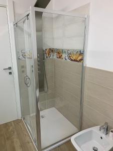 une douche avec une porte en verre à côté d'un lavabo dans l'établissement Oasi verde, à Aoste