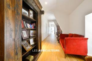 a living room with a red couch and a book shelf at Hôtellerie Nouvelle de Villemartin in Morigny-Champigny