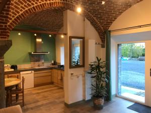 a kitchen with a brick ceiling and an open door at La gaîté de louvignies in Louvignies-Quesnoy