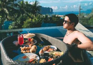 
a man sitting at a picnic table with a plate of food at Krabi Tipa Resort - SHA EXTRA PLUS in Ao Nang Beach

