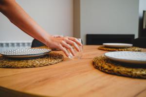 een persoon die reikt naar een glas op een houten tafel bij Apartamentos Turia Teruel in Teruel