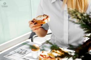 a woman holding a pastry in her hand next to a table at 4- you Family in Metamorfosi