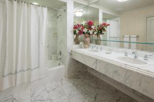La salle de bains est pourvue de 2 lavabos, d'une douche et d'un miroir. dans l'établissement The Bristol Hotel Campbell San Jose, à Campbell