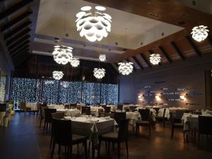 a dining room with tables and chairs and chandeliers at Chalet Greenwood in Beloe Ozero