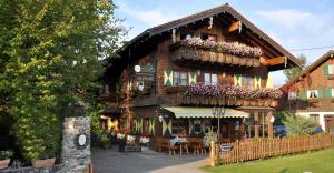 a large wooden house with flowers on the facade at Alphirt Ferienwohnungen in Fischen