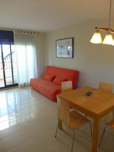un soggiorno con divano rosso e tavolo di Rentalmar Residencial La Cala a Miami Platja