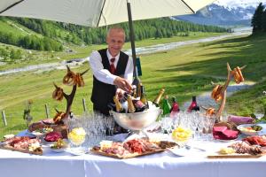 Un uomo sta preparando il cibo su un tavolo di Hotel Roseg-Gletscher a Pontresina