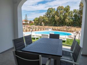un patio con tavolo, sedie e piscina di villetta con piscina budoni affitti spiaggia 700 mt a Budoni