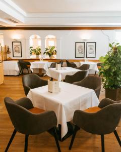 un restaurante con mesas blancas, sillas y plantas en Thermenhotel Vier Jahreszeiten, en Lutzmannsburg