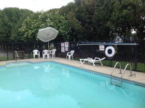 a swimming pool with chairs and an umbrella at Days Inn by Wyndham Clinton in Clinton