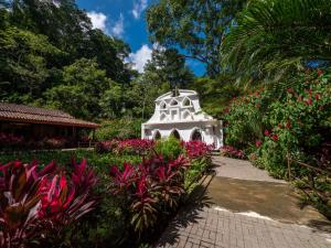 a white building in a garden with flowers at Villa Lapas Jungle Village in Jacó