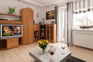 a living room with a tv and a vase of flowers on a table at Haus Möwe Wohnung Leuchttürmchen in Hörnum