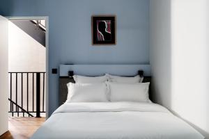 sypialnia z białym łóżkiem i niebieską ścianą w obiekcie Edgar Suites Notre-Dame - Lagrange w Paryżu