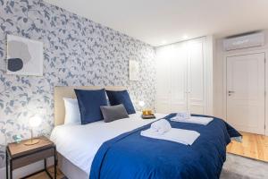 een slaapkamer met een blauw en wit bed met handdoeken erop bij Elegant Downtown 1BR Flat w/ AC by LovelyStay in Porto