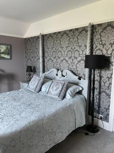 a bedroom with a white bed and a wall with wallpaper at The Eagle Tavern in Faringdon