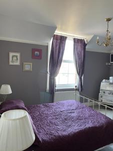 a bedroom with a purple bed and a window at The Eagle Tavern in Faringdon