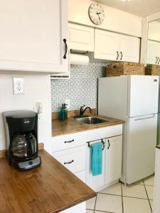 a kitchen with a white refrigerator and a sink at Beach Daze - Ocean front at Symphony Beach Club! in Ormond Beach