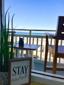 a table and chair on a balcony with a view of the beach at Beach Daze - Ocean front at Symphony Beach Club! in Ormond Beach