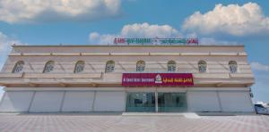 duży biały budynek z czerwonym napisem w obiekcie الكامل للشقق الفندقية w mieście Al Kāmil