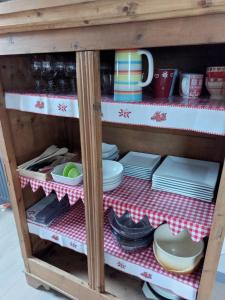 a cabinet with plates and dishes on a red and white table cloth at Les Marmottes in Les Étalons +8 photos