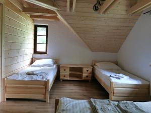 two twin beds in a room with wooden walls at DOMEK POD CZEREMCHĄ in Zawóz