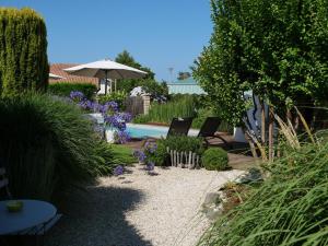 um jardim com duas cadeiras e um guarda-sol em Chambres d'hôtes Villa Surcouf em Andernos-les-Bains