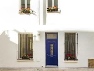 Sitges Rustic Apartments في سيتجيس: مبنى أبيض مع باب ونوافذ زرقاء
