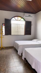 two beds in a room with a window at SOLAR DA BRAN Mosqueiro - Pará in Belém