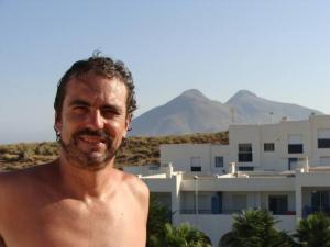 een man zonder shirt die voor een gebouw staat bij Isleta del Moro TERRAZA VISTAS MAR Exclusiva 60 m2 WIFI in La Isleta del Moro