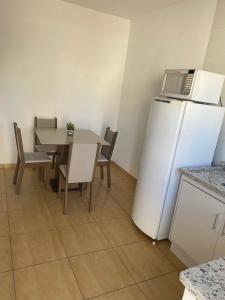 a kitchen with a table and a white refrigerator at AP frente à praça bem localizado in São José