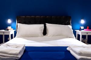um quarto azul com uma cama com lençóis brancos e almofadas em NAPOLI IN BLU MAISON em Nápoles