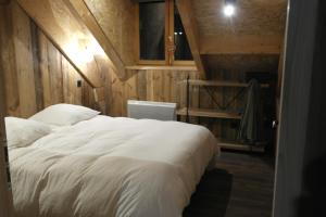 a bedroom with a large white bed with wooden walls at Maison de village au coeur d'Allos in Allos