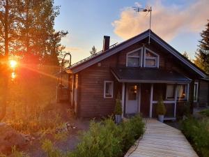 a wooden house with the sun setting behind it at Villa Laiskajaakko in Vimpeli