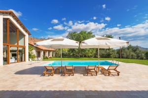 een zwembad met twee parasols en twee stoelen en een tafel en twee stoelen bij Villa Elva Nafplio in Nafplio