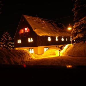 Ferienwohnungen Schönherr في Schlettau: منزل مغطى بالثلج في الليل