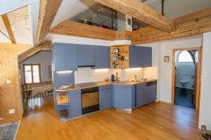 a kitchen with blue cabinets and a wooden floor at Apartment Bügl Grond 124 in Scuol