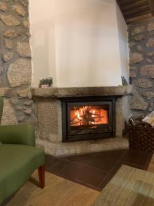 a living room with a fireplace with a green chair at Casas da Peneda - Geres in Gavieira