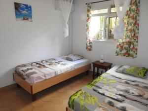 a bedroom with two beds and a window at Villa Nanou , Haut de villa calme et petite vue sur Mer in Bouillante