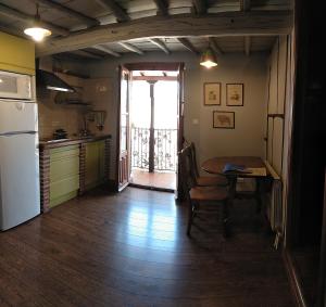 cocina con mesa, nevera y puerta en Alojamientos La Herrera, en San Esteban de la Sierra