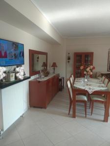 uma sala de jantar com uma mesa com cadeiras e uma televisão em Sweet luxury apartment Peraia em Perea