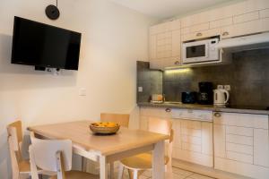 a kitchen with a table with chairs and a microwave at Résidence Pierre & Vacances Le Domaine du Bois de la Grée in Pornichet