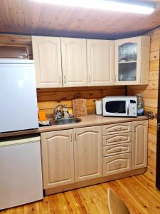 La cuisine est équipée d'un réfrigérateur blanc et d'un four micro-ondes. dans l'établissement Деревянный 2-х комнатный домик, à Kiev